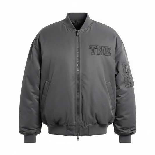 Charcoal gray oversized bomber jacket with dark gray TNE embroidered logo on ghost mannequin